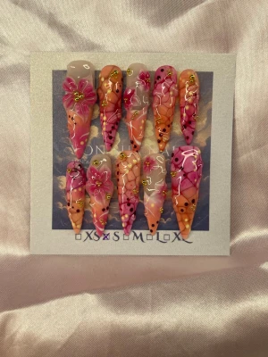 Ibiza (S);Extra Long Stiletto - Säljer ett set extra långa handgjorda press-on naglar i stilettoform med färgstark design i rosa, orange och nude. Naglarna är handmålade och har handgjorda blommor, guldiga detaljer och vinröda/gula prickar för en unik look. Perfekt för dig som vill sticka ut med kreativa och trendiga naglar.S: 15 mm, 11,5 mm, 12 mm, 11 mm, 9 mm 