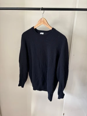 Stickad tröja - Klassisk svart stickad tröja med rund hals och långa ärmar. Tröjan har en rak passform och ribbade muddar vid ärmslut och nederkant. Perfekt basplagg för lager på lager och funkar till det mesta.