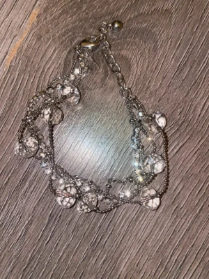 Silvrigt armband med glaspärlor - Snyggt armband i silverfärgad metall med flera kedjor och genomskinliga glaspärlor. Armbandet har ett justerbart spänne och pärlorna ger ett glittrigt intryck. Perfekt för dig som gillar detaljer och vill ha något som sticker ut lite extra.