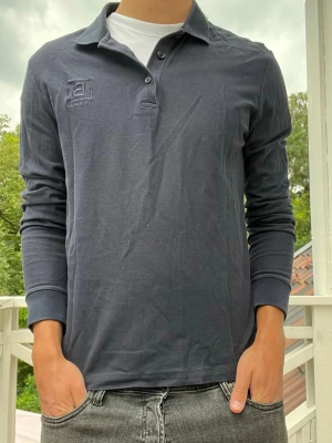 Burberry långärmad piké  - Snygg långärmad piké från Burberry London som passar bra till det mesta. clean logga. Nästan blå/svart färg. Hör av er!
