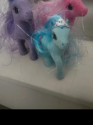 3 st.Häst figurer glitter - Tre häst figurer i glitterdesign, en blå med tiara och blå man, en lila med lila man och en rosa med rosa man. Alla har långa glittriga manar och stora ögon. Perfekta för samling eller lek.