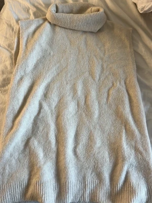Vit ärmlös stickad tröja  - Mysig vit ärmlös tröja i mjukt stickat material. Tröjan har en bred ribbad polokrage och ribbade detaljer vid nederkanten. Säljer pågrund av att jag inte använder den så ofta. Liten i storlek, passar alla. Är själv en XS/ S storlek, men denna som är XL är inte en vanlig XL storlek! Så passar alla!