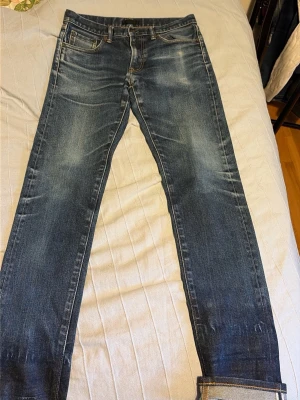 Mörkblå selvedge jeans från uniqlo - Säljer ett par mörkblå selvedge jeans med raka ben och klassisk femficksdesign. Jeansen har snygga slitningar och kontrastsömmar. Tillverkade i kraftigt denimtyg med tydlig selvedge-detalj vid uppviket. Perfekta för dig som gillar tidlös och clean stil. Unika fades o honeycombs. 