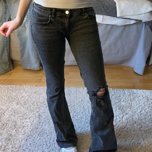 Svarta bootcut jeans med slitning - Säljer ett par svarta bootcut jeans från Gina Tricot. Har sytt om dem till lågmidjat, där av defekten på sista bilden (syns inte med byxorna på)