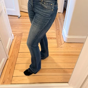 Blå bootcut jeans med raw edge 7 for all Mankind - Snygga blå bootcut jeans med hög midja och klassisk femficksdesign. Storlek 26. Tyvärr behöver de en sväng till skräddaren då en söm gått upp i midjan därav det lägre priset