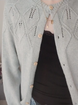 Jättefin kofta  - Säljer en ljusblå stickad kofta med fina hålmönster och träknappar. Koftan har rund halsringning och långa ärmar. Perfekt för lager på lager och ger en söt vintagekänsla till din outfit. Sitter som en xxs -xs. Skriv ifall du vill ha mått! 