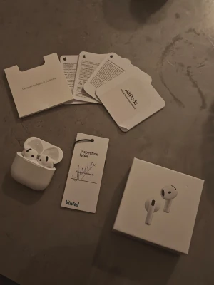 Apple AirPods 4 med brusreducering  - Säljer ett par vita Apple AirPods med trådlöst laddningsetui. Hörlurarna har en stilren och minimalistisk design i plast och kommer med kartong, manualer och inspektionslapp. Perfekta för musik, samtal och träning tack vare smidig Bluetooth-anslutning.