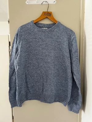 Blåmelerad stickad tröja - En stilren blåmelerad stickad tröja med rund halsringning och ribbade muddar vid ärmslut och nederkant. Perfekt för lager-på-lager och enkel att matcha med jeans eller kjol.