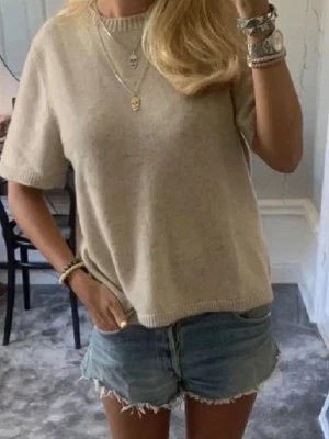 Beige stickad topp Soft Goat - Mysig beige stickad topp från Soft Goat med rund halsringning och korta ärmar. Toppen har en enkel, klassisk design med ribbade kanter vid ärmslut och nederkant. Tröjan har en liten defekt framtill men syns knappt. Nypris 2200kr⭐️