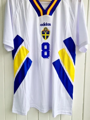 Klas Ingesson - Sverige - VM 1994 - Säljer en klassiska fotbollströja, Klas Ingessons svenska vita bortamatchtröja från VM 1994 i USA. Tröjan är en reprint i nyskick.  Aldrig använd.    Storlek: Large