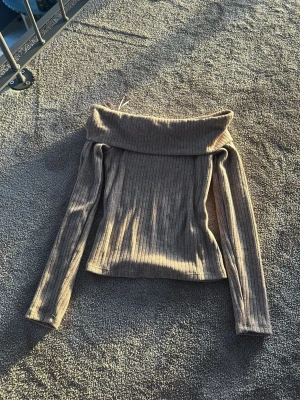 Beige off shoulder tröja Stradivarius - Trendig beige off shoulder tröja från Stradivarius i ribbat material. Långa ärmar och bred krage som kan vikas ner över axlarna. Perfekt för dig som vill ha en stilren och snygg look med en twist. Passar till både jeans och kjol.