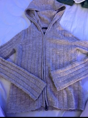  ribbad hoodie - Mysig  hoodie  med dragkedja framtill och ribbad struktur. Tröjan har huva och långa ärmar, samt en mjuk och stretchig känsla i materialet. Perfekt för chill dagar eller när du vill ha något bekvämt och stilrent.