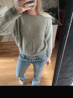 Grön stickad tröja med pärlor  - Grön stickad tröja med pärlor på som har ett liten hål långt nere på baksidan. 