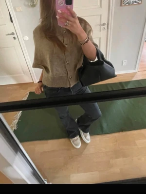 Beige kortärmad kofta med knappar - Kortärmad beige kofta med ribbad nederkant och knäppning framtill. Avslappnad passform och mjukt material, perfekt för lager på lager. Passar till jeans eller kjol för en trendig look.