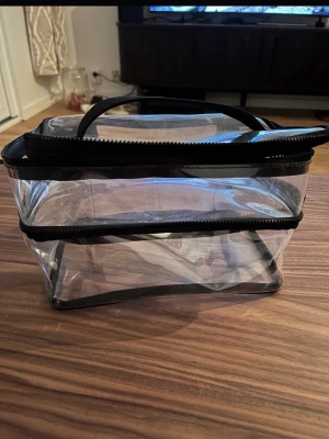 Transparent necessär med svart kant - Säljer en genomskinlig necessär i plast med svarta detaljer och dragkedja från HM