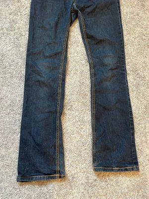 Mörkblå boutcut jeans - Snygga mörkblå jeans med boutcut passform och klassiska kontrastsömmar. Jeansen har fem fickor och är tillverkade i ett slitstarkt denimtyg. Perfekta för en avslappnad och stilren look.