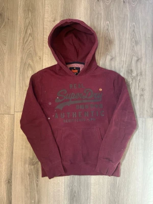 Vinröd hoodie från Superdry - Säljer en vinröd hoodie från Superdry med stor logga och japansk text på bröstet🤗 True to size ( Saknar snören) Men inget man tänker på🙌🏻 pris ej hugget i sten😇