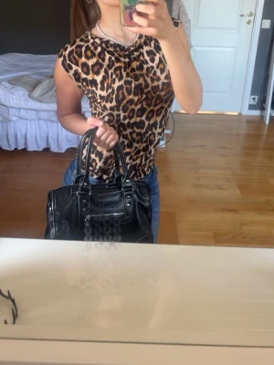 Leopardmönstrad ärmlös topp - Säljer en snygg ärmlös topp med leopardmönster. Toppen har rund halsringning och en tight passform som framhäver figuren. Perfekt för dig som vill sticka ut med ett djuriskt print. Materialet känns mjukt och stretchigt, vilket gör den bekväm att bära hela dagen.