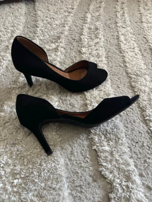 svarta klackar- mocka - Svarta klackar k i mocka-liknande material. Skorna har öppen tå och  siluett. Sköna och bekväma, knappt använda 