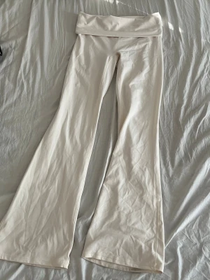 Vida beige leggings med hög midja - Säljer ett par snygga beige leggings med utsvängda ben och hög midja. De är stretchiga och mjuka, perfekta för en avslappnad och trendig look. Passar till crop tops eller oversized tröjor. Materialet känns lent och följsamt.