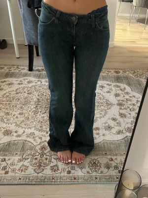 Weekday low waist bootcut jeans - Säljer ett par mörkblå bootcut jeans med låg midja och klassiska fem fickor. Jeansen har en lätt utsvängd passform nedtill och stängs med knapp och dragkedja. Perfekta för dig som gillar en retroinspirerad look.