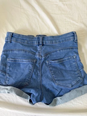 Blå denimshorts med uppvik - Säljer ett par klassiska blå denimshorts från Gina Tricot. Shortsen har Lågmidjade och nya. Pris går att diskutera och jag kan skicka de snabbt! 💕