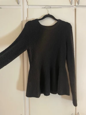 Svart stickad tröja från H&M - Säljer en svart populär stickad tröja från H&M med rund halsringning och lång ärm. Tröjan har en lätt utsvängd passform nedtill och är gjord i ett mjukt, ribbat material som känns skönt mot huden. Perfekt för lager på lager under kyliga dagar.