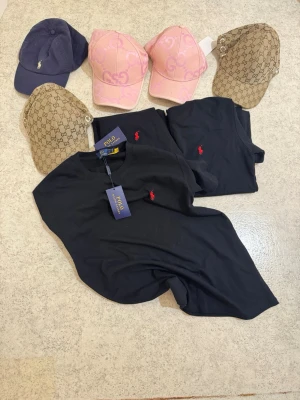 Kläder - Säljer 3 styckna helt nya svarta t-shirts och 5 styckna kepsar. Allt dammar i en liten byrå därför är priset så lågt. PRISET ÄR FAST.