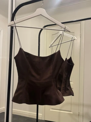 Zara topp - Topp från Zara, aldrig använd. Stl XS. Brun med smala axelband & figursydd/utsvängd. Dragkedja i sidan. Kan hämtas el skickas.