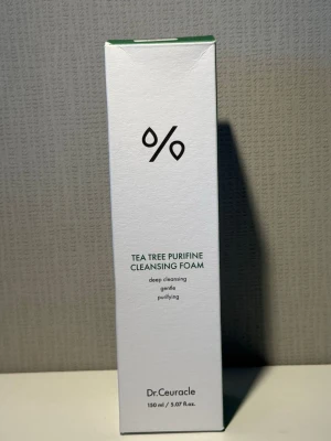 Tea Tree Purifine Cleansing Foam - Rengöringsskum från Dr.Ceuracle med tea tree-extrakt. Mild formula som rengör på djupet, är skonsam och hjälper till att rena huden. Förpackningen är vit med gröna detaljer och rymmer 150 ml.