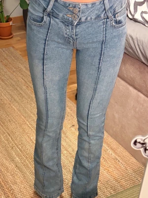Bootcut jeans med pressveck🌸 - Säljer ett par ljusblå bootcut jeans med markerade pressveck framtill och dubbla knappar i midjan. Jeansen har klassiska fickor både fram och bak och är tillverkade i stretchigt denimtyg för skön passform.
