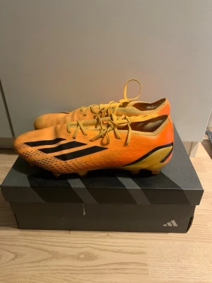 Adidas orange fotbollsskor speedportal - Säljer ett par grymma orange fotbollsskor från Adidas med svarta detaljer och klassiska stripes på sidorna. Skorna har snörning och är tillverkade i ett lätt syntetmaterial som ger bra bollkontroll och grepp på planen. Säljer för dem är för små.pris kan diskuteras
