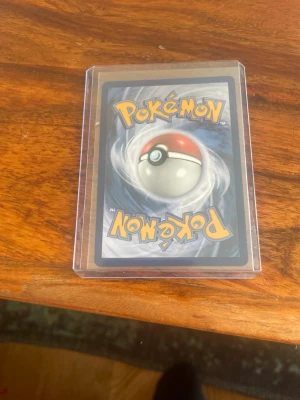 Mega Zygarde EX Pokémonkort - Säljer ett Mega Zygarde EX Pokémonkort med färgstark design i grönt, svart och gult. Kortet har 310 HP och attacker som Gaia Wave och Nullifying Zero. Kortet ligger i ett genomskinligt plastfodral för extra skydd.