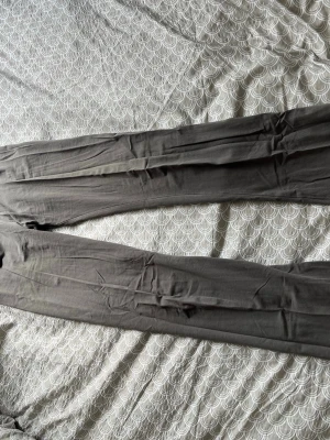 Grå leggings med bred midjeresår - Säljer ett par grå leggings med bred midjeresår och smal passform. Materialet är mjukt och stretchigt, perfekt för en avslappnad look. Färgen är neutralgrå och designen är enkel utan synliga loggor eller detaljer. Går att vika ner byxorna vid midjan