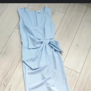 Babyblå balklänning - En babyblå balklänning som är öppen i ryggen. En rosett längs ryggen och volanger längs benen. Pris kan diskuteras.