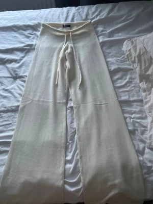 Vita mjukisbyxor från Gina Tricot - Säljer ett matchande sett från Gina Tricot. Byxorna är i storlek XS och tröjan i S. Byxorna har breda ben och är i stickat material som känns riktigt skönt mot huden. Använd endast 1 gång. 