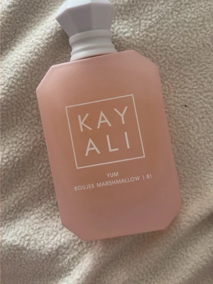 Kayali Yum Boujee Marshmallow 81 EdP - Kayali Yum Boujee Marshmallow 81 är en parfym i en matt, ljusrosa flaska med vit, multifasetterad kork. Doften är söt och gourmand, inspirerad av marshmallows. Flaskan har en modern, kantig design och rymmer 100 ml Eau de Parfum Intense. Köpt från en säljare på Vinted och endast testad .