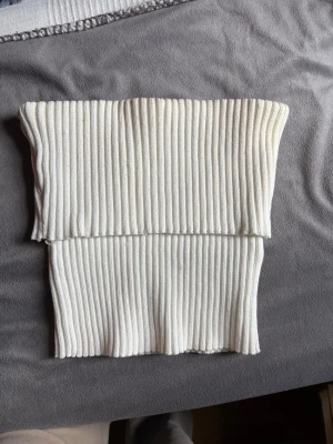 Vit ribbad bandeau topp från Zara - Säljer en vit ribbad bandeau topp från Zara. Toppen är axelbandslös och har en croppad passform med breda ribbade ränder som ger en snygg struktur.