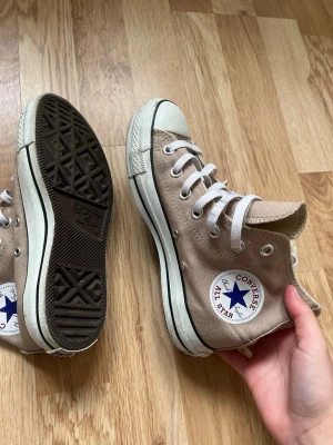 Ljusbruna Converse  - Säljer ett par bruna Converse All Star high tops skor. Storlek 36 