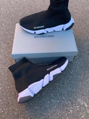  svarta sneakers - Svarta sneakers med vit och svart chunky sula. Stickad ovandel i stretchigt tyg som sitter som en strumpa runt foten. logga på sidan och sulan. Modern och sportig design med hög komfort.