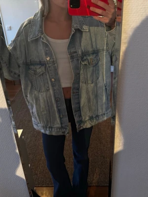 Oversized ljusblå jeansjacka - Säljer en oversized ljusblå jeansjacka med klassisk knappstängning och stora bröstfickor. Jackan har en avslappnad passform och bred krage, perfekt för att skapa en cool och trendig look. Passar dig som gillar streetstyle och vintage vibes.