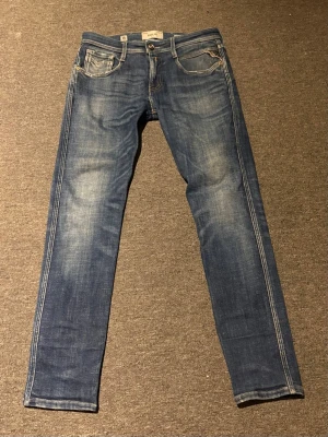Replay anbass jeans - Snygga blå slim fit jeans från Replay med klassisk femficksdesign och slitna detaljer. Jeansen har ljusare partier på låren och knäna för en cool, använd look. Tillverkade i bomull med en liten stretch för extra komfort. Storlek:29,30. Hör av er vid övriga frågor!!😁