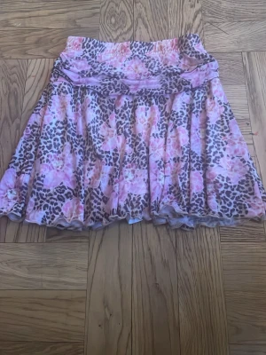Minikjol med leopard mönster och blommor - Säljer en kjol med shorts i. Köptes secondhand men har aldrig använts av mig (eftersom storleken inte passade). Det står inte var den är ifrån, färgerna är lite starkare än vad de ser ut att vara på bilden skulle jag säga. Väldigt bra skick även fast den är secondhand.