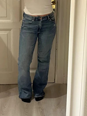 Blå raka jeans med slitningar - Säljer ett par blå jeans med rak passform och lätt slitna detaljer vid fickorna.  Knappt använda 