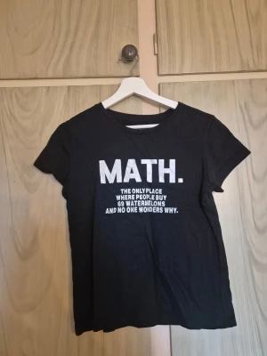 Svart t-shirt med texten - Svart t-shirt med vit text på bröstet: 'MATH. The only place where people buy 69 watermelons and no one wonders why.' Klassisk rund hals och korta ärmar. Väldigt mjuk i tyget.            Alla kläder rollas innan dom skickas hem då det finns katt i hemmet🐈 Jag stryker och tvättar INTE innan jag skickar det får du stå för själv så det blir som du vill ha det🤗