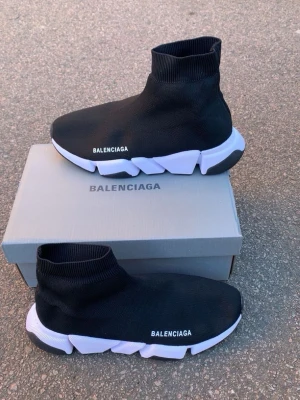 Balenciaga Speed Trainer svarta sneakers - Svarta Balenciaga Speed Trainer sneakers med vit chunky sula och stickad ovandel i textil. Strumpliknande passform och Balenciaga-logga på sidan. Perfekta för dig som gillar en futuristisk och clean stil.