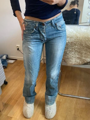 Blå raka jeans  - Säljer ett par blå jeans med rak passform och låg midja. Jeansen har slitna detaljer, klassiska fem fickor och ljus tvätt. Perfekta för en avslappnad och trendig look. Storlek S