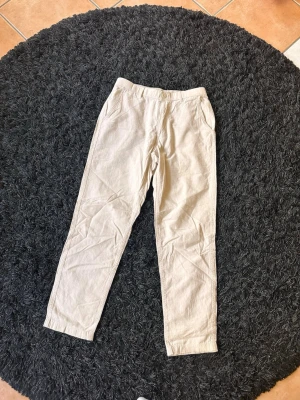 Beiga linnebyxor med raka ben - Snygga beiga linnebyxor med raka ben och avslappnad passform. Byxorna har resår i midjan bak, sidfickor fram och två fickor bak. Perfekta för en chill och stilren look under varma dagar. Tillverkade i ett lätt och luftigt linnematerial.