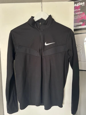 Svart långärmad träningströja Nike - Svart långärmad träningströja från Nike med halv dragkedja och hög krage.