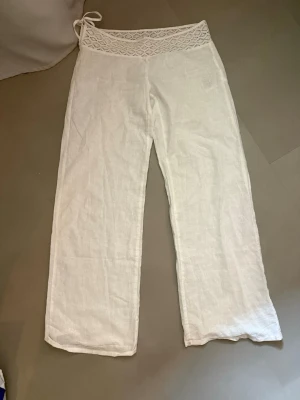 Vita linnebyxor med spetsdetalj - Säljer ett par vita linnebyxor med bred spetskant och knytband i midjan. Från Gina tricot